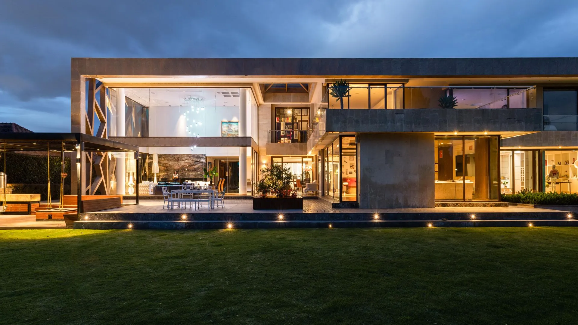 Kivilágított, modern család villa alkonyatkor, ápolt kerttel